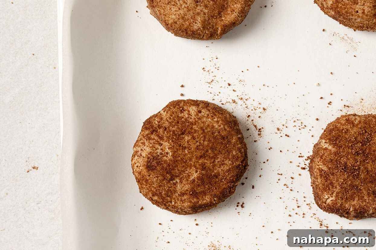 The cinnamon-sugar coated snickerdoodle dough balls flattened on a baking sheet, ready for the oven.