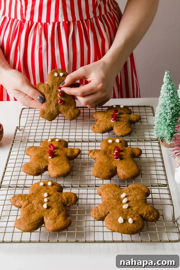 Woman in a red and white dress holding a plate of decorated AIP gingerbread cookies.