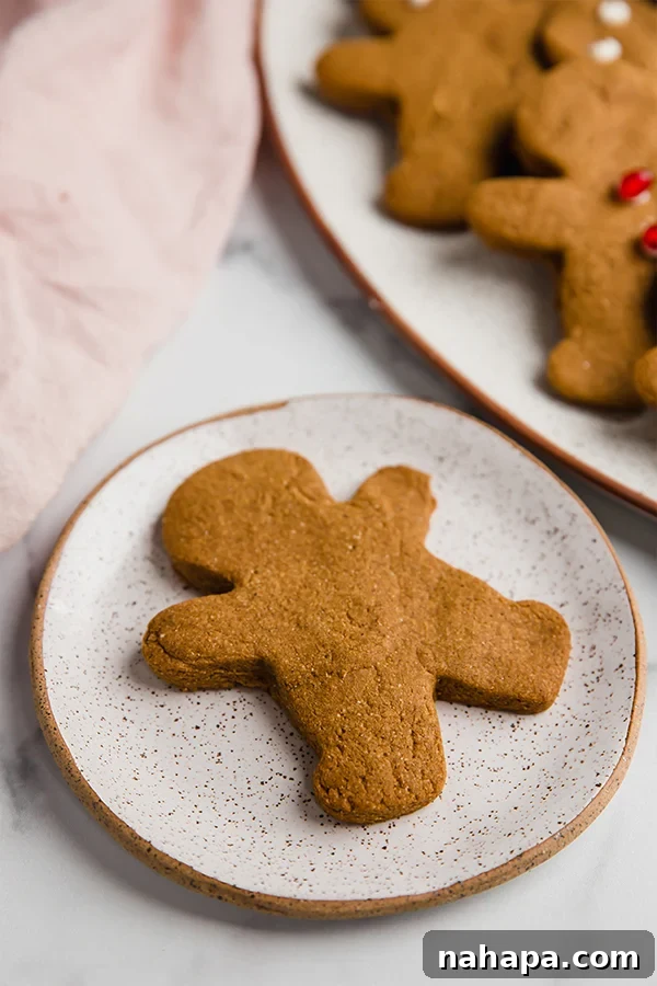 Single gingerbread cookie on a small round white plate, decorated beautifully.