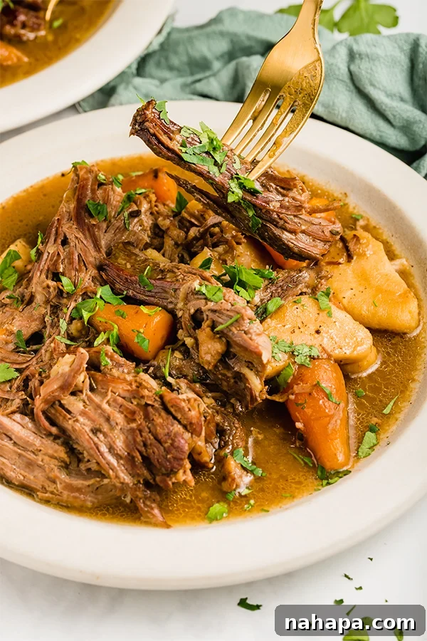 slow cooker pot roast in bowl with fork