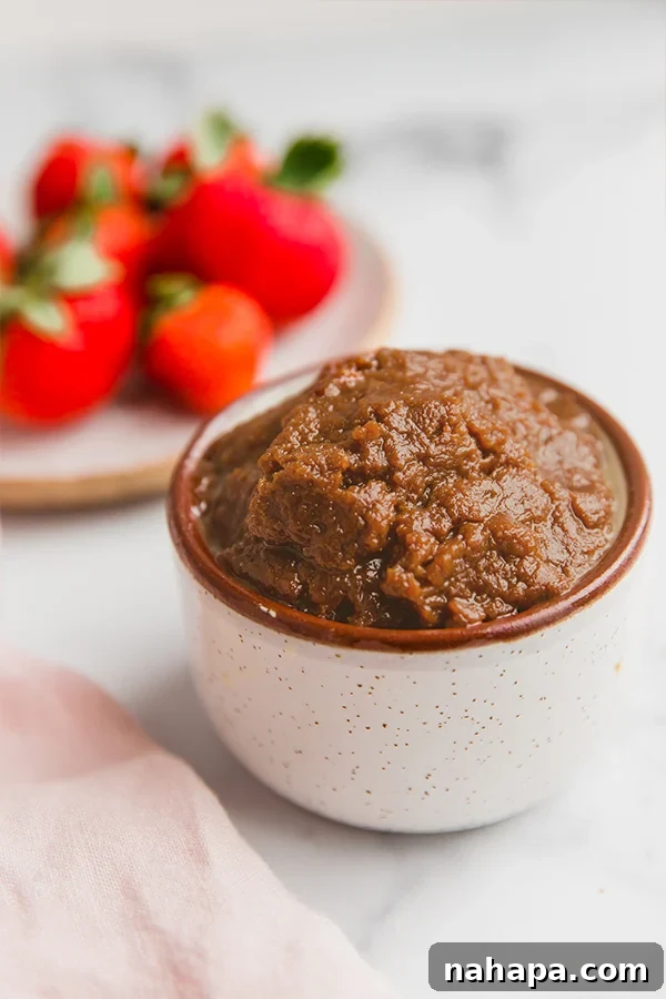 AIP cookie butter in a small cup, garnished with strawberries on a plate