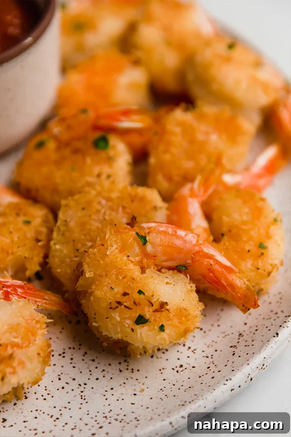 Close-up of perfectly golden-brown oven-baked coconut shrimp arranged on a white plate