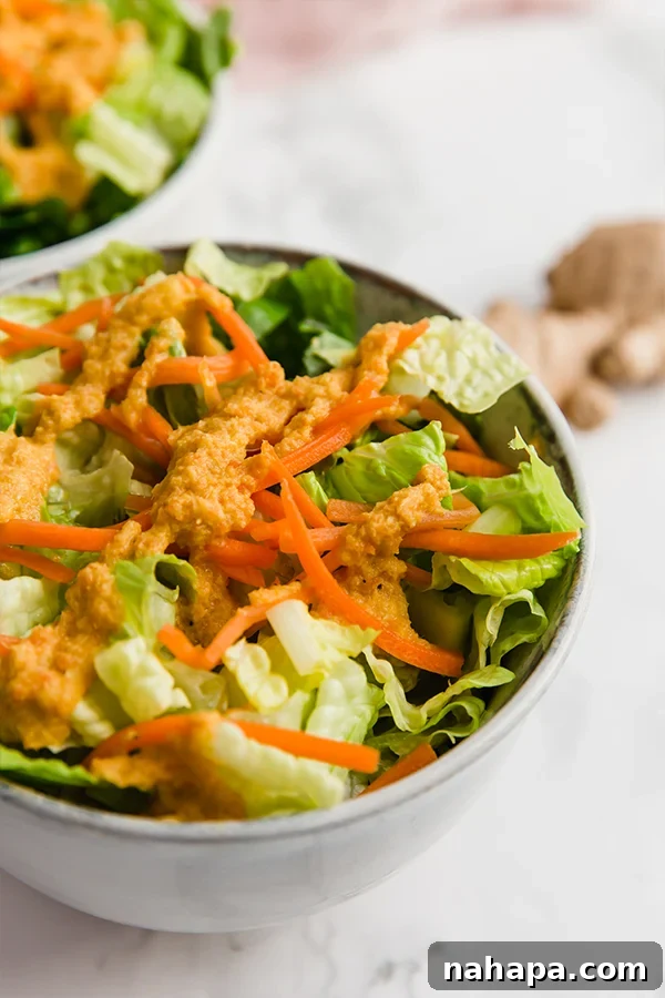 Homemade Japanese restaurant-style ginger salad dressing drizzled generously over a fresh green salad in a bowl