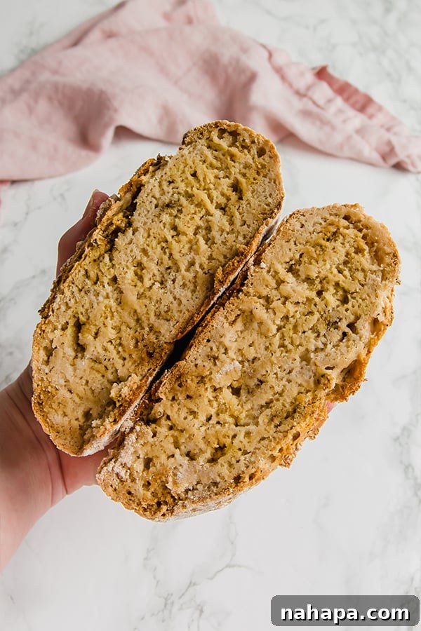 A rustic loaf of no-knead gluten-free bread, sliced in half to show its tender interior, flavored with garlic and herbs