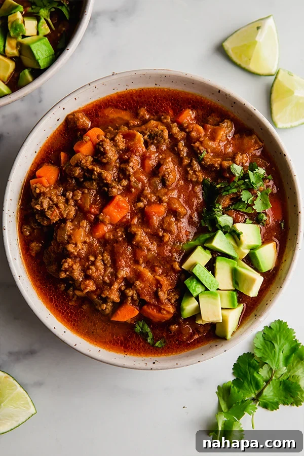 chili in a bowl with avocado and lime slices, showcasing vibrant colors