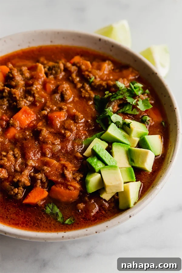 chili in a bowl with avocado and cilantro garnish, close-up shot