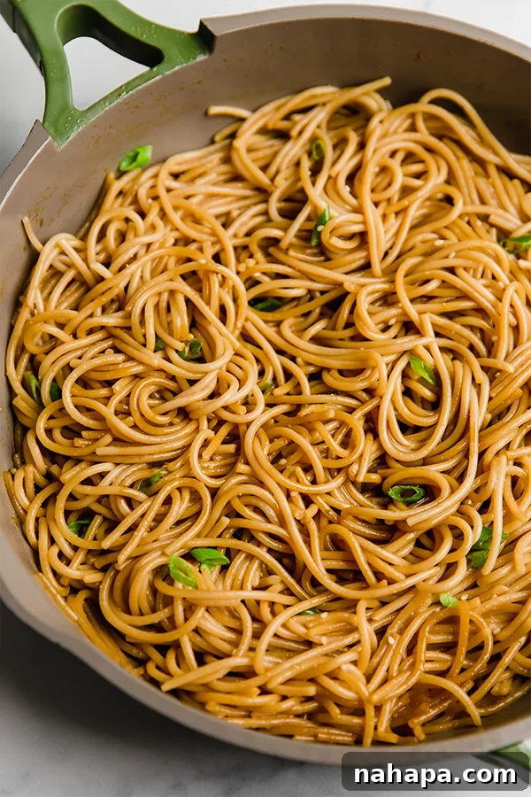 Sizzling homemade hibachi noodles in a skillet, coated in a delicious sauce.