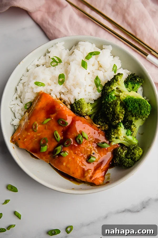 teriyaki salmon bowl with broccoli and rice, chopsticks on the side