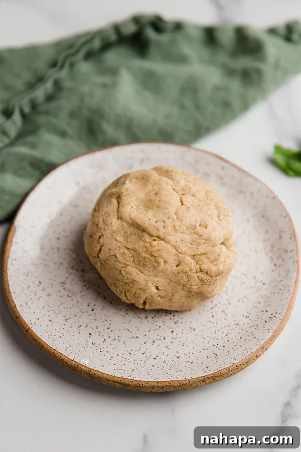 Pizza dough formed into a perfect ball on a baking sheet, ready for flattening