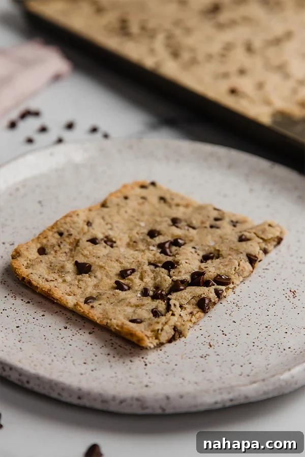 Three slices of gluten-free, paleo, and vegan sheet pan chocolate chip cookies artfully arranged, showcasing their soft interior and delightful chocolate.