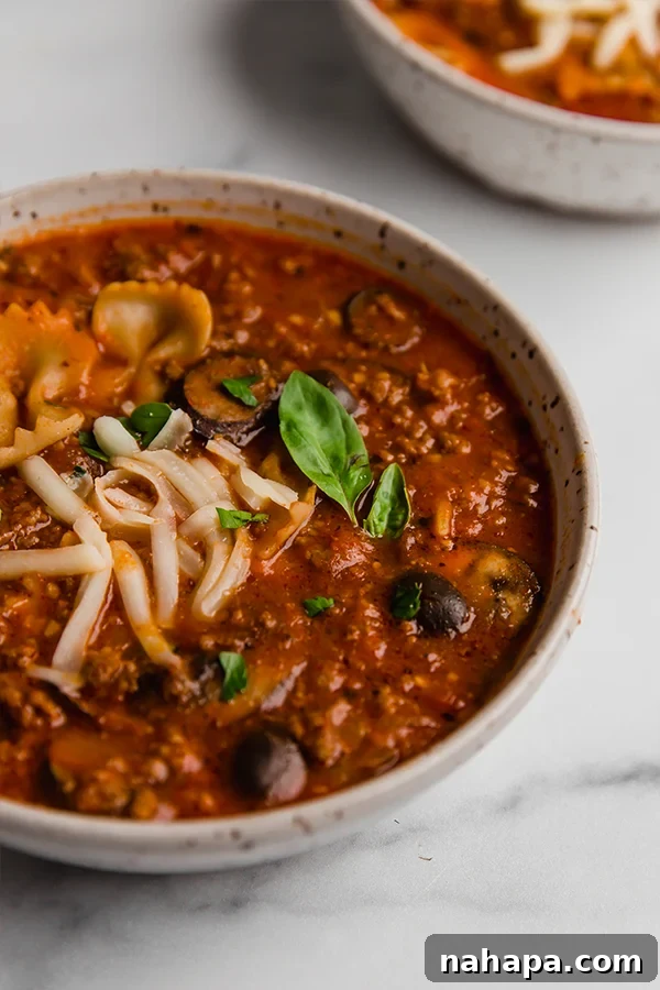 A top-down view of gluten-free pizza soup in a bowl with fresh basil