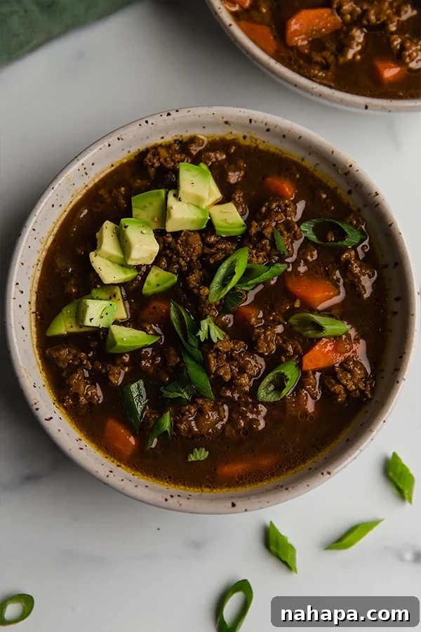 A vibrant bowl of Asian Inspired Chili, garnished with fresh herbs and avocado, ready to be enjoyed as a hearty meal.