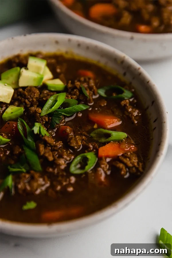 A tantalizing close-up of Asian Inspired Chili in a bowl, showcasing its rich texture and vibrant colors, topped with fresh garnishes.