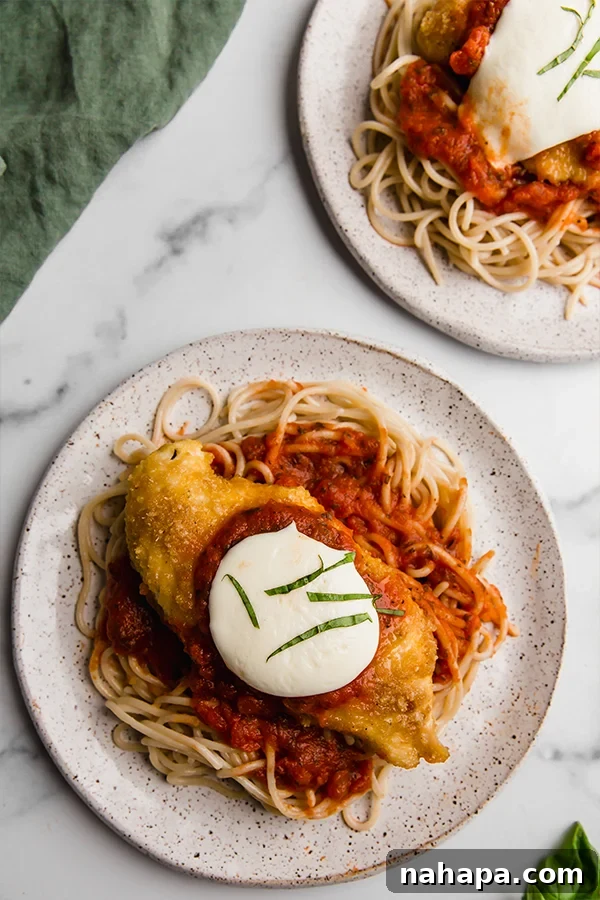 Two plates of chicken parmesan with spaghetti