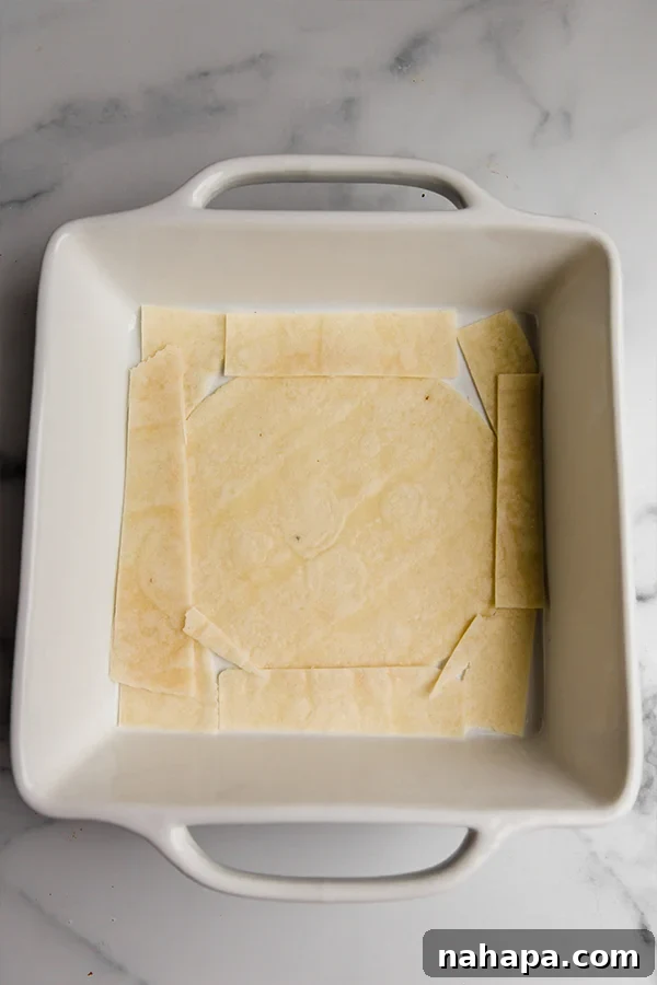 Grain-free tortillas lining the bottom of a baking dish, preparing for the first layer of the taco casserole