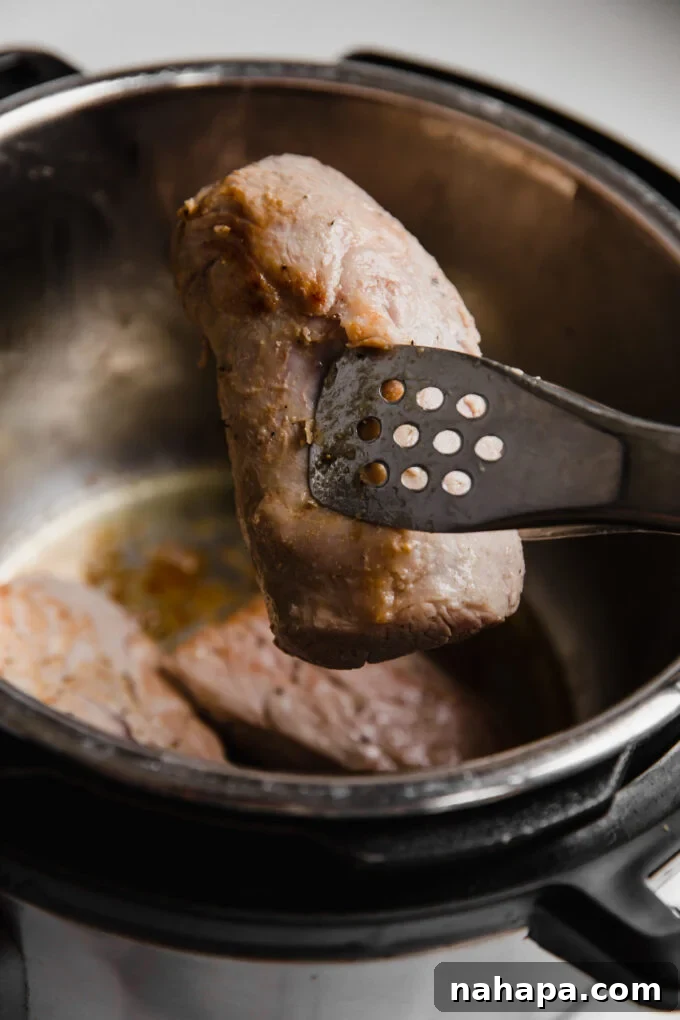 instant pot pork tenderloin slice in tongs