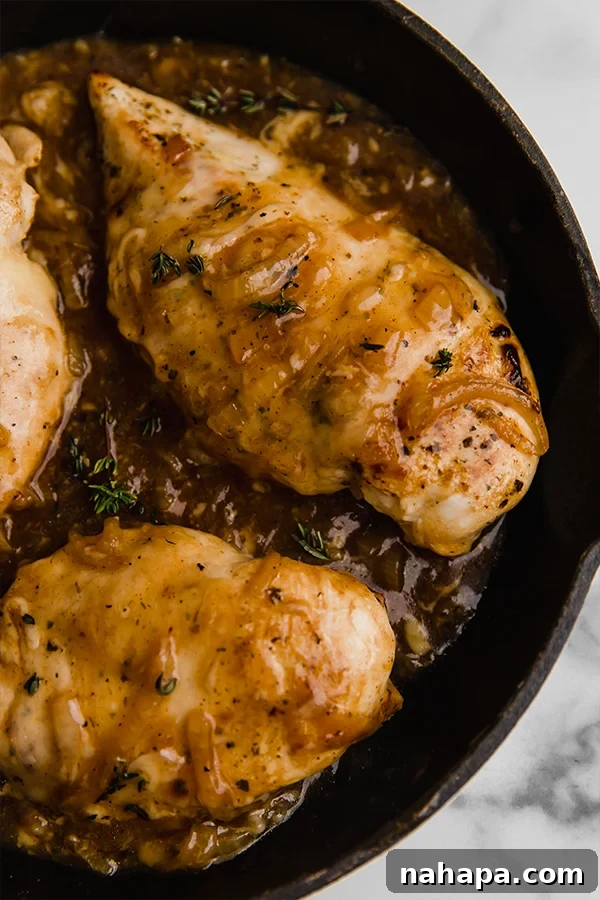 Paleo and AIP French Onion Chicken 4 Close up of French onion chicken in cast iron skillet, showcasing the golden onions and melted cheese