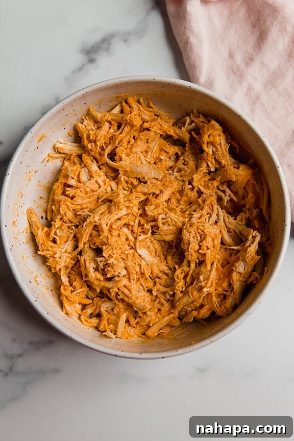 Buffalo chicken filling mixed in a glass bowl, ready to be stuffed into zucchini