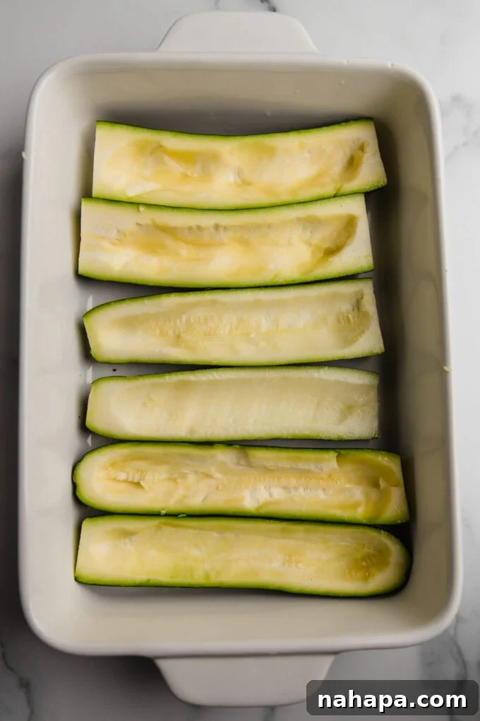 Savory Zucchini Taco Boats Low Carb Paleo Whole30 AIP 3 Scooped out zucchini halves are neatly arranged in a baking dish, perfectly prepared and ready to be stuffed with the savory taco filling, illustrating the preparation stage of the recipe.