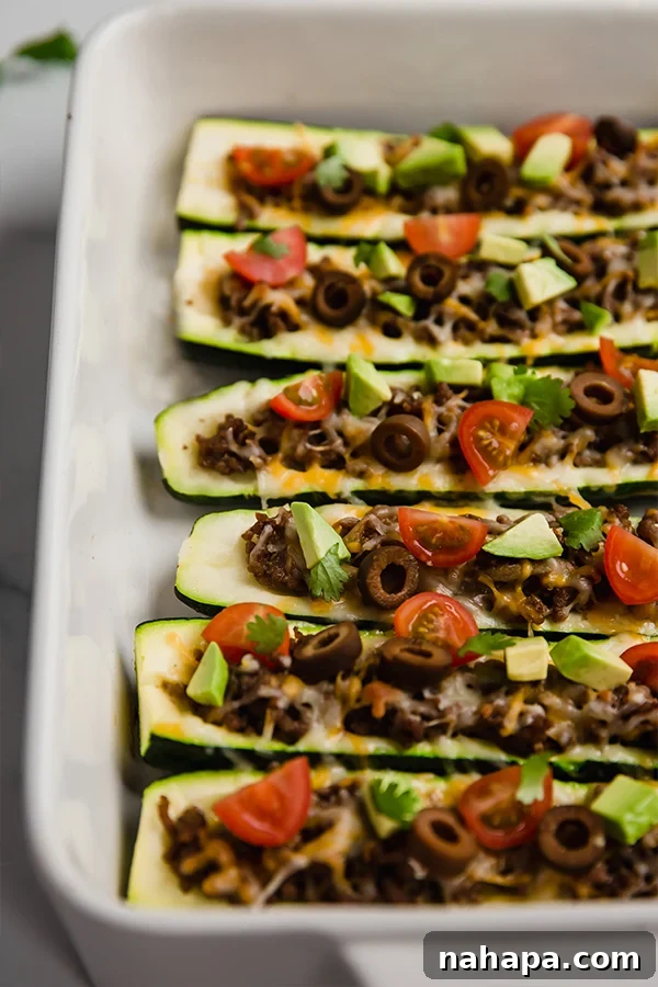 Savory Zucchini Taco Boats Low Carb Paleo Whole30 AIP 4 A baking dish filled with several baked taco stuffed zucchini boats, each generously loaded with savory meat and ready for the final fresh toppings, showcasing a tempting and hearty meal.
