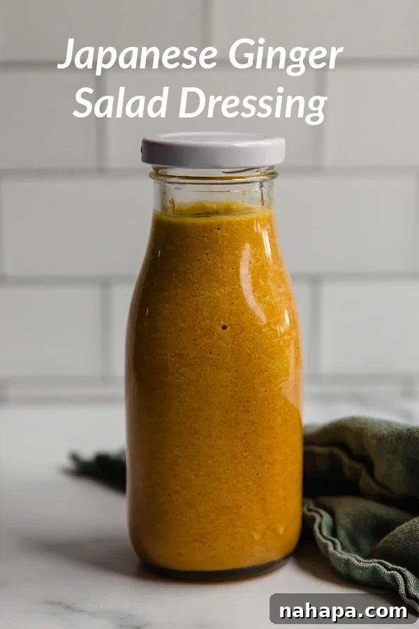 A bowl of fresh salad with crisp lettuce and shredded carrots, topped with a rich, orange-hued Japanese-style ginger dressing.