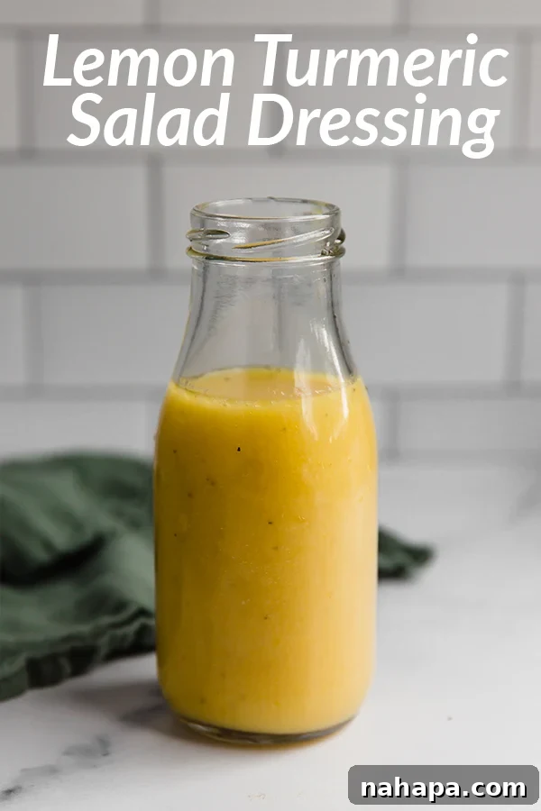 A small bowl of vibrant yellow lemon turmeric dressing with a spoon, ready to be drizzled over a salad.