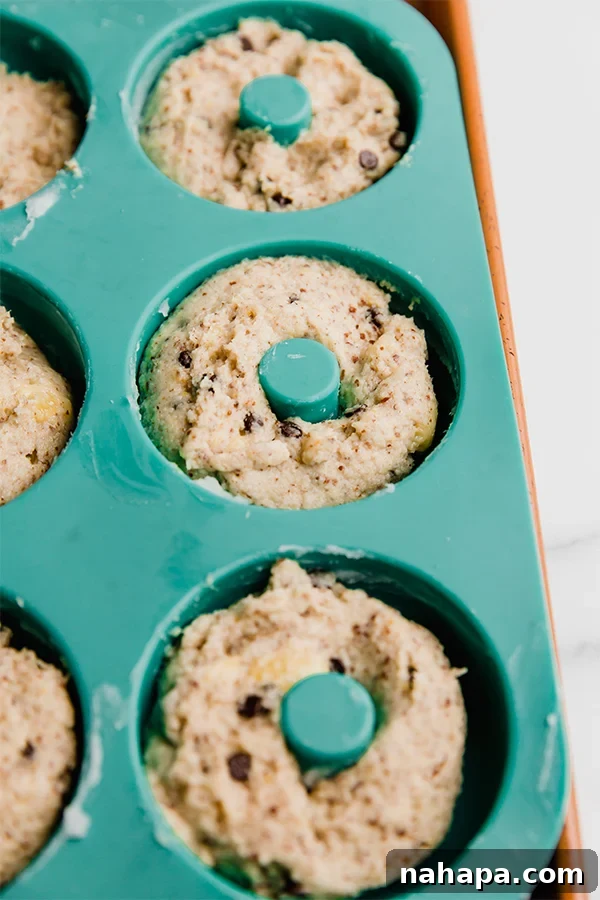 Banana bread donuts piped into a donut pan, ready for baking.