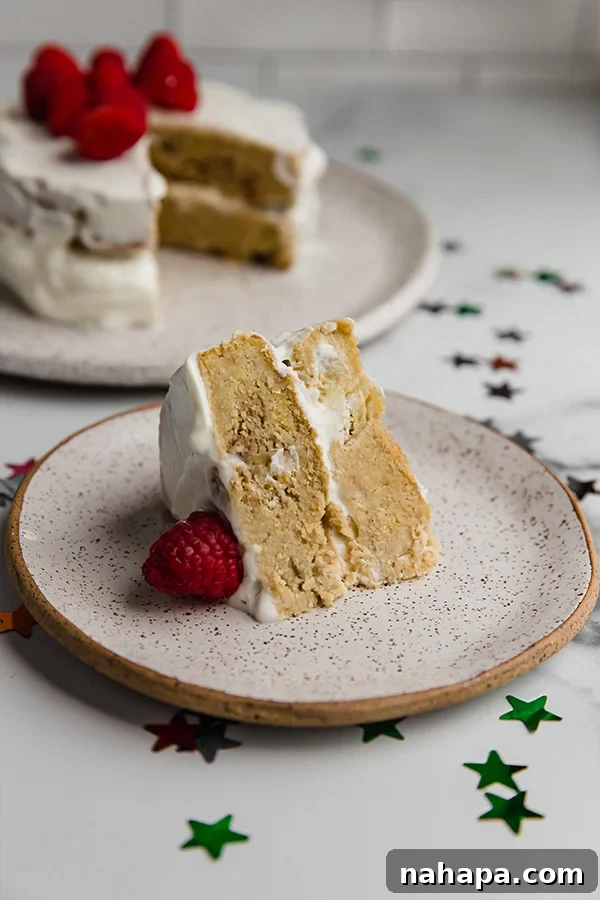 A charming slice of healthy baby smash cake on a plate, featuring a moist texture and a creamy dairy-free frosting, adorned with fresh raspberries.