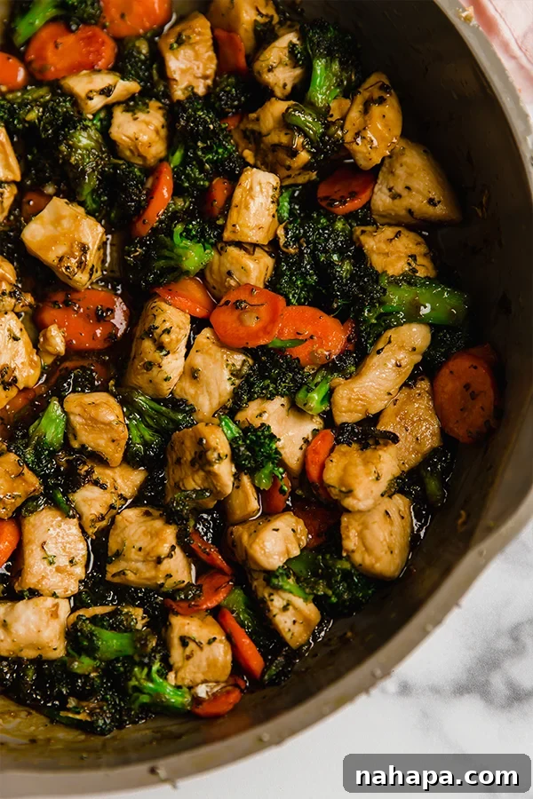 Chicken stir fry in frying pan, being tossed with sauce