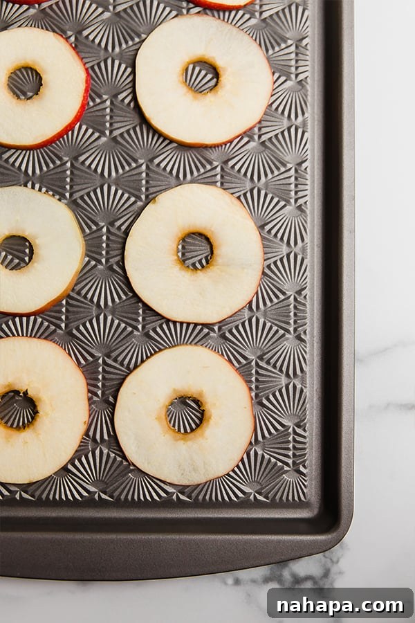 Freshly sliced apple rings ready for toppings laid out on a sheet pan
