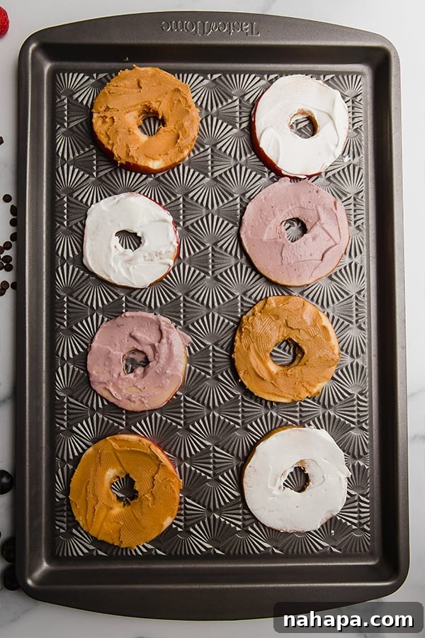 Apple slices on a sheet pan, artfully topped with creamy almond butter and vibrant coconut yogurt