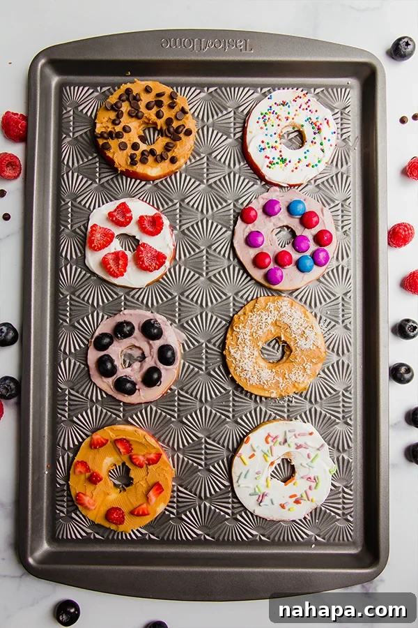 Close-up of apple 'donuts' adorned with fresh berries, chocolate chips, and shredded coconut, ready to be enjoyed