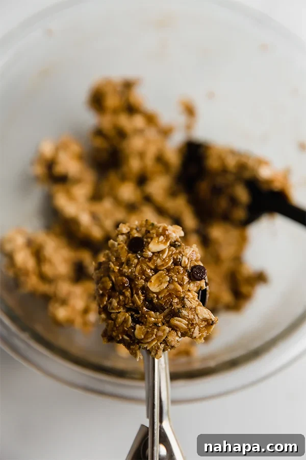 Close-up image of a cookie scoop forming an energy bite, demonstrating the rolling process.