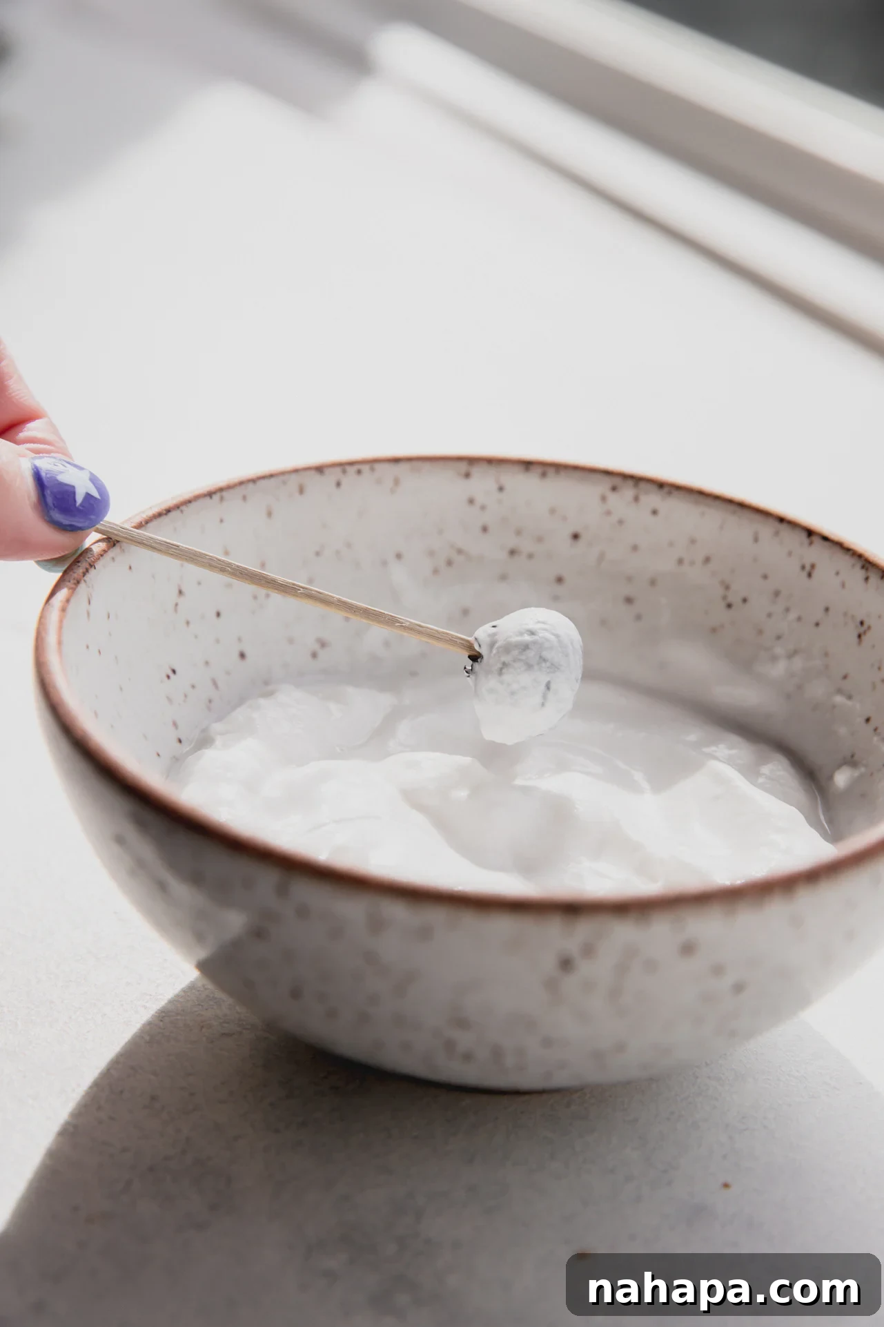 Blueberry on a toothpick coated in yogurt.