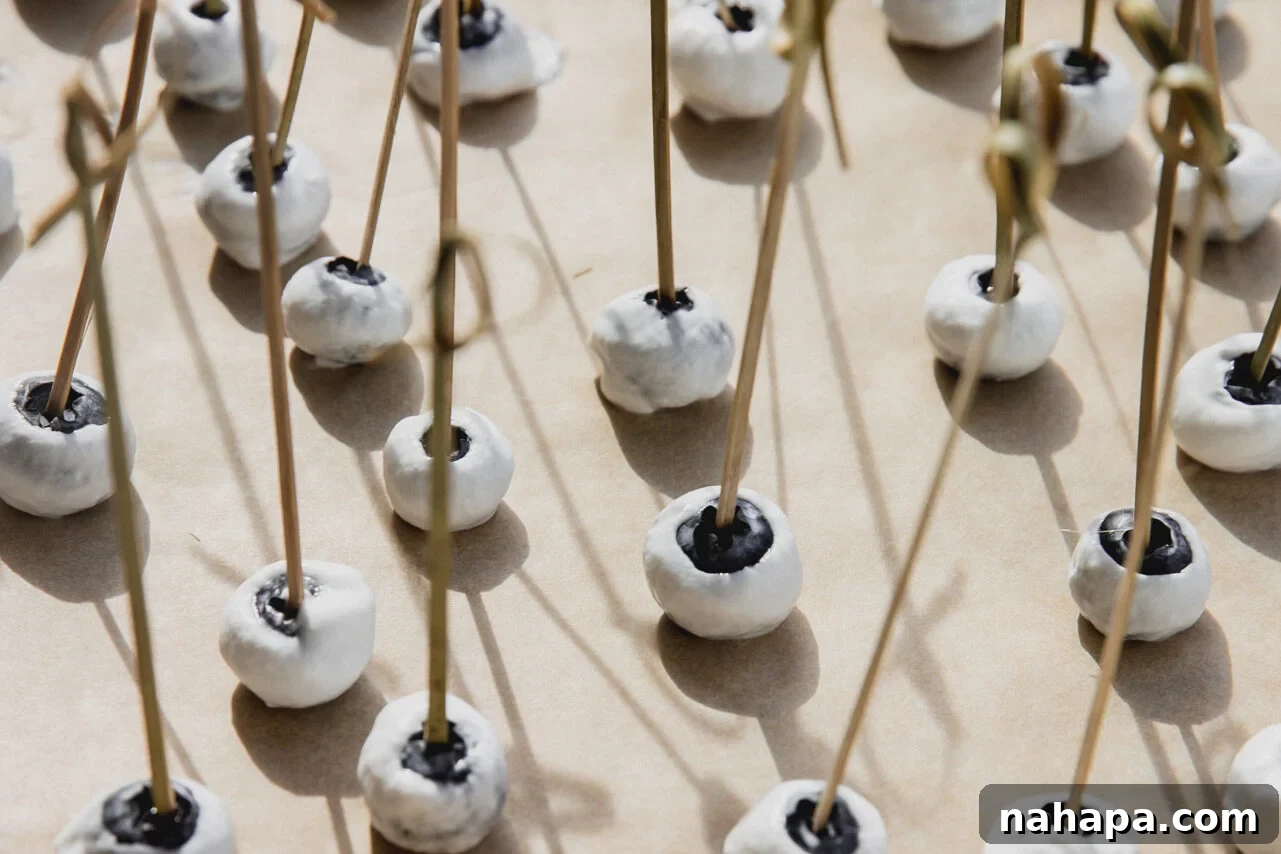 Blueberries coated in yogurt and frozen on a baking sheet.