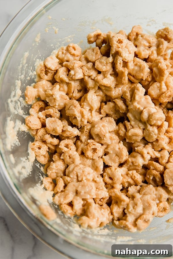 Cereal mixed with the creamy binding ingredients in a large bowl, ready to be pressed into a pan