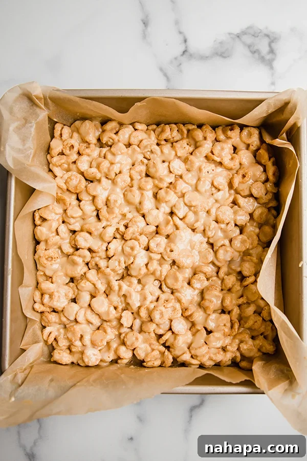 Cereal bars mixture pressed firmly into a square pan and ready to set in the fridge