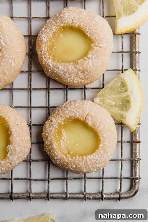 Lemon thumbprint cookies cooling on a wire rack, showing a detailed top-down view of the golden crust and lemon curd filling.