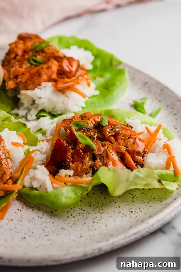 Two neatly arranged salmon lettuce wraps on a white ceramic plate, demonstrating a colorful and balanced meal presentation.