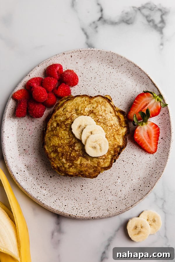 A stack of banana pancakes topped with fresh banana slices and a drizzle of syrup.