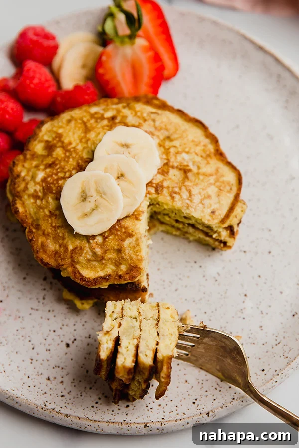 Close-up of a banana pancake being cut with a fork, showing its soft and fluffy texture.