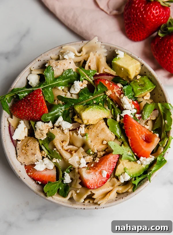 Strawberry balsamic pasta salad in a bowl on a counter, part of the recipe card image.