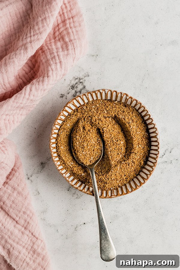 Homemade paleo spice rub mixed in a glass bowl with a wooden spoon, ready to season the pork for a slow cooker BBQ pulled pork recipe.