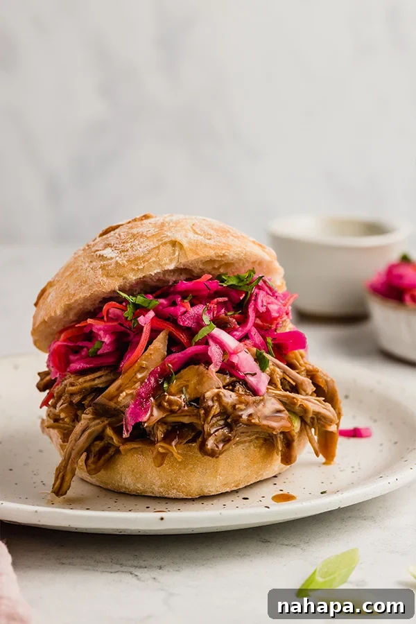 BBQ pulled pork served on a toasted sourdough bun with creamy coleslaw and a slice of dill pickle on a rustic plate, ready for a delicious meal.