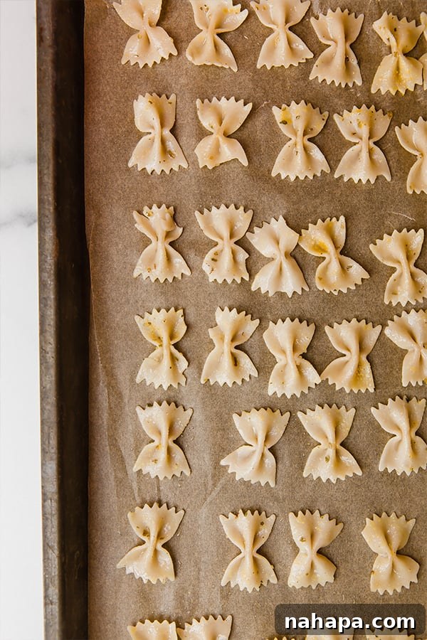 Pasta arranged in a single layer on a baking sheet, ready for the oven
