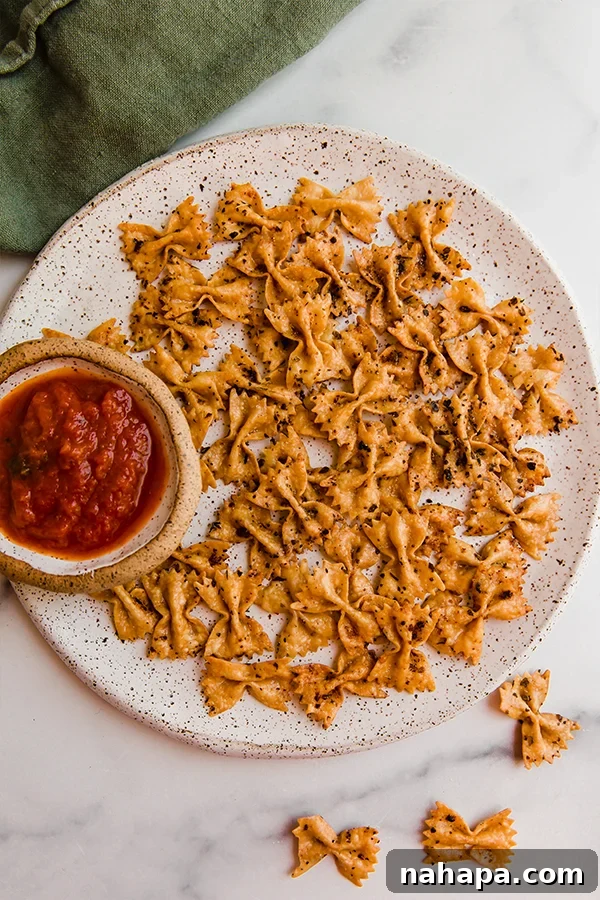 Pasta chips in an air fryer basket, halfway through cooking