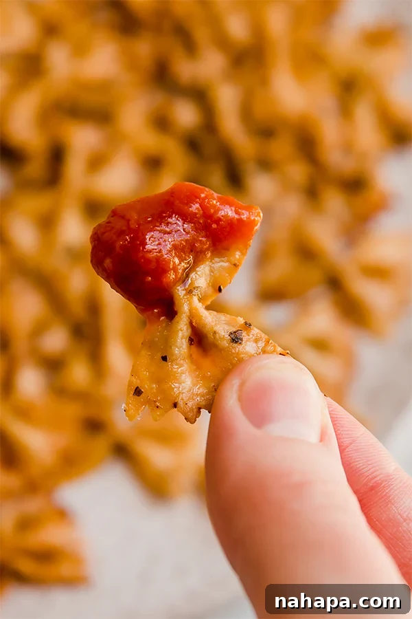 A bowl of crispy pasta chips next to a serving of marinara sauce for dipping