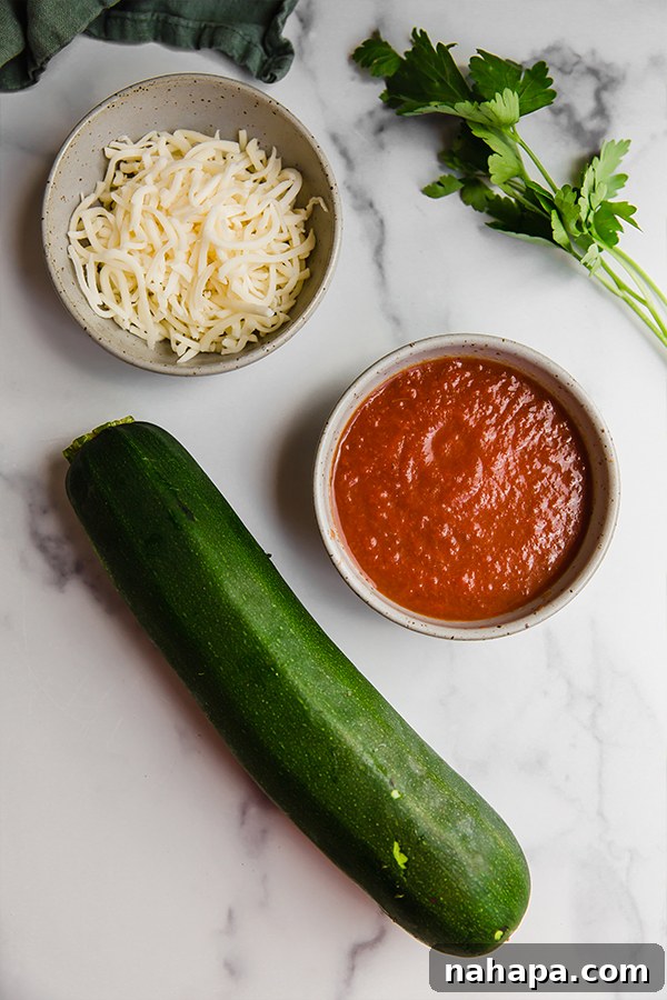 Ingredients for Zucchini Pizza Bites laid out in bowls on a kitchen counter, including sliced zucchini, marinara sauce, and mozzarella cheese.