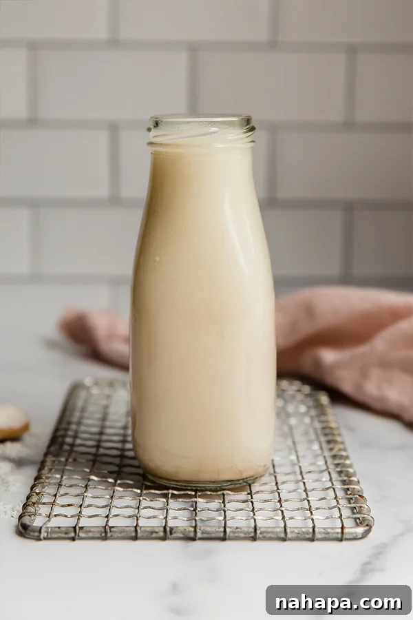 Homemade coconut milk in a glass jar, next to a coconut.