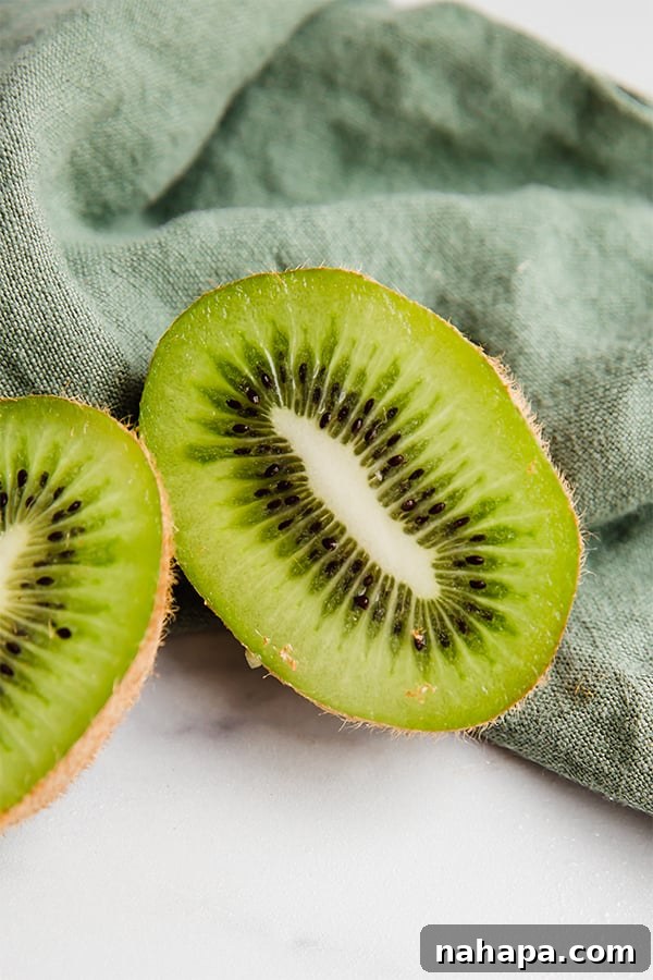 Fresh kiwi sliced in half on a wooden cutting board